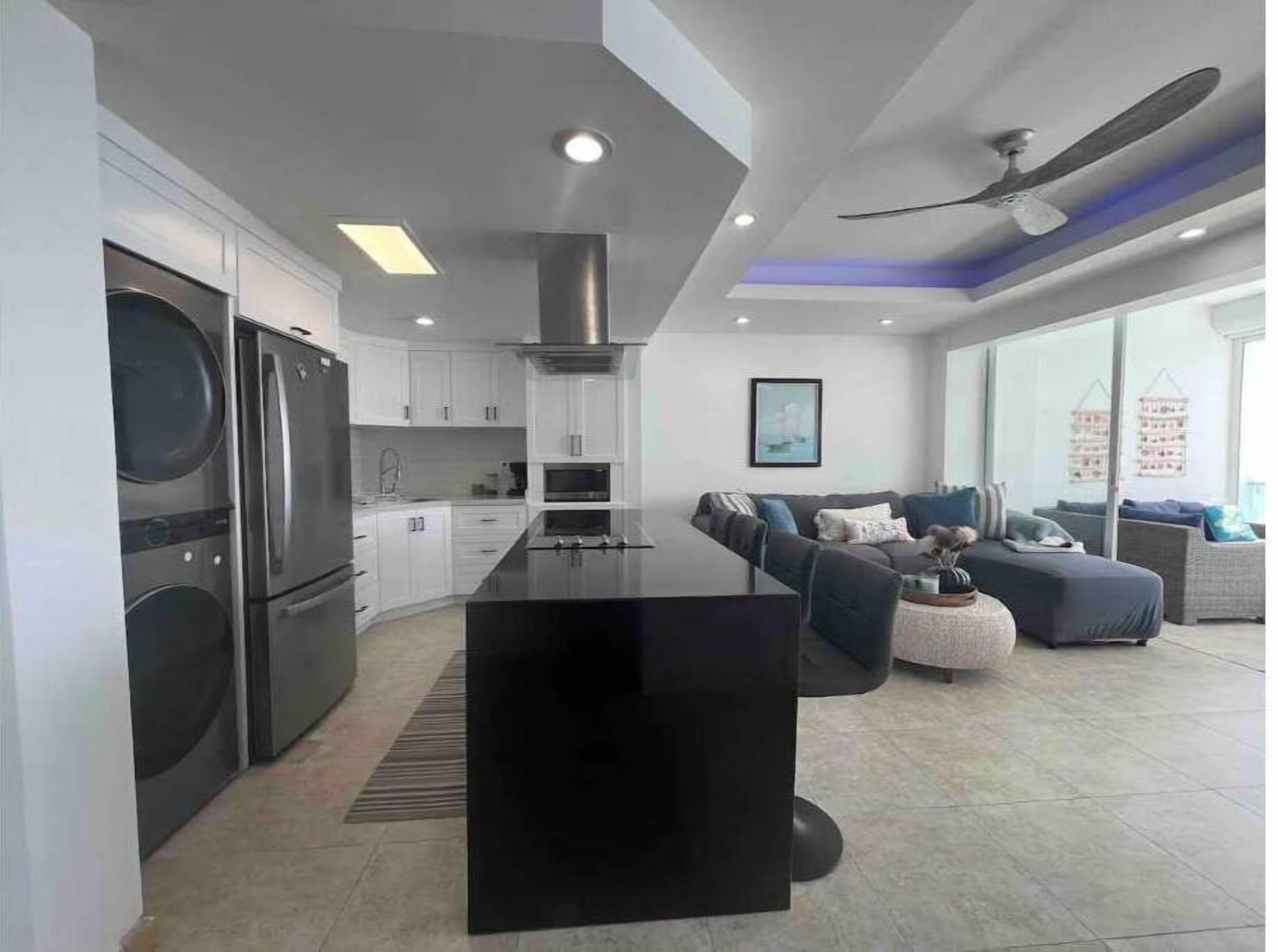 A modern kitchen with a central island, built-in appliances, and a dining area with a sofa and coffee table.