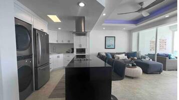 A modern kitchen with a central island, built-in appliances, and a dining area with a sofa and coffee table.