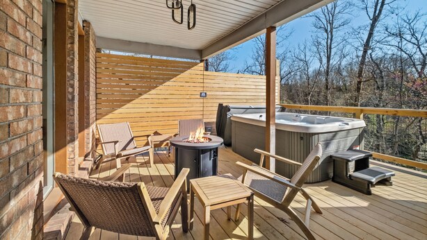 A covered deck with outdoor furniture, a fire pit, and a hot tub. - Mural House A: On The Trails > Private Hot Tub > Fire Pit > EV Charger (Bentonville)