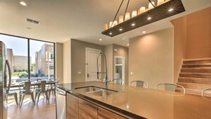 A modern kitchen with a large island, stainless steel appliances, and a view of the outdoors.