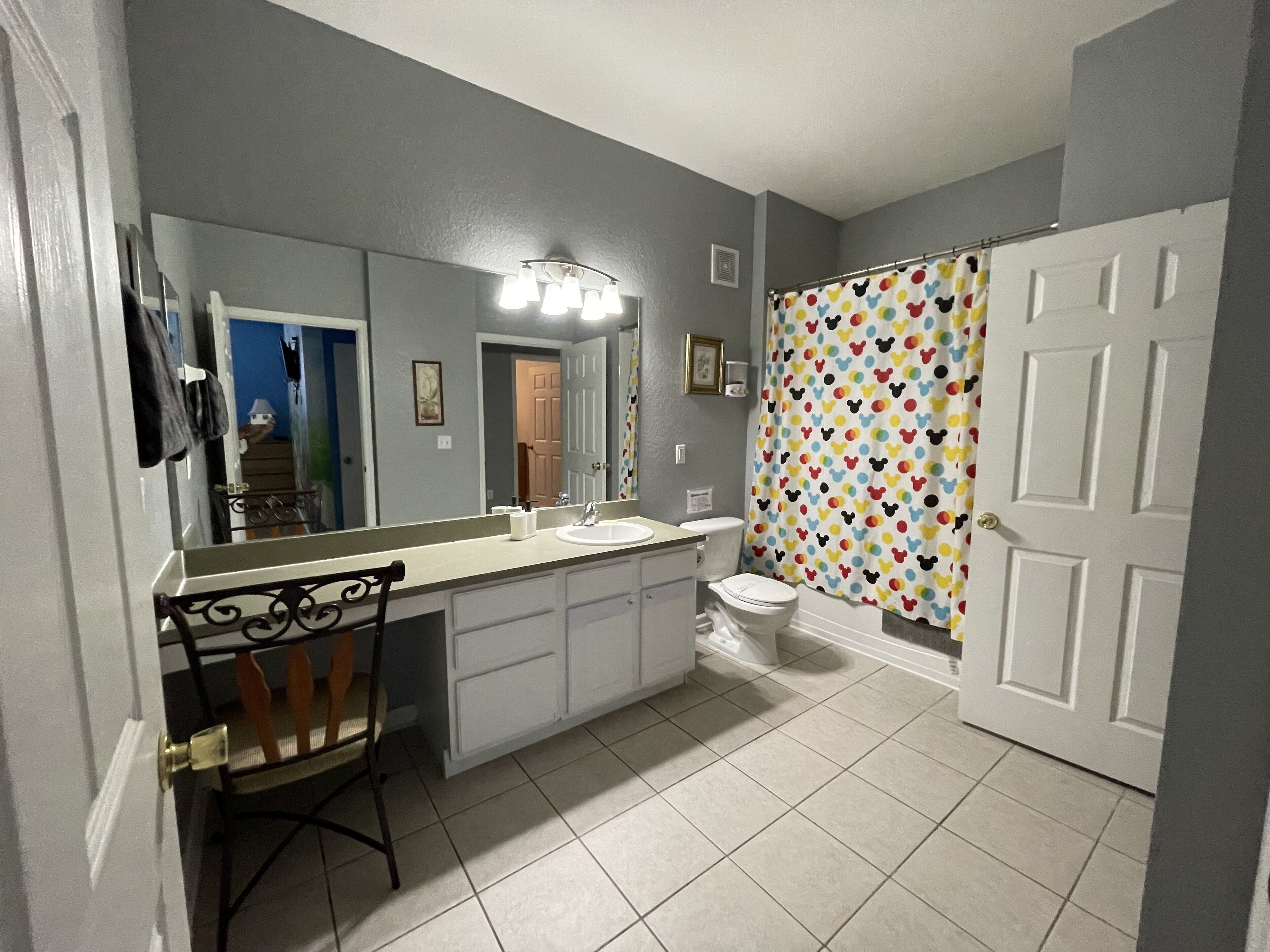 A bathroom with a vanity, sink, mirror, and toilet.