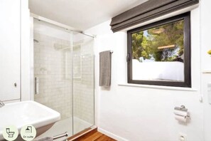 Bathroom features a glass-enclosed shower, white sink, and towel rack.