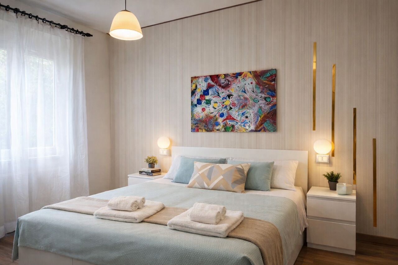 Una camera da letto moderna con un letto grande, due comodini, un quadro appeso al muro e una finestra con tende leggere.