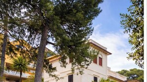 A multi-story building with a central entrance, surrounded by trees and a parking area. - Hotel Villa Pina (Senigallia)