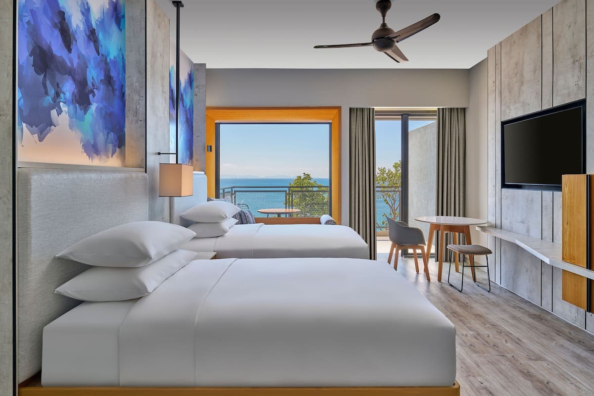 A modern hotel room with a large bed, a desk, and a TV.
