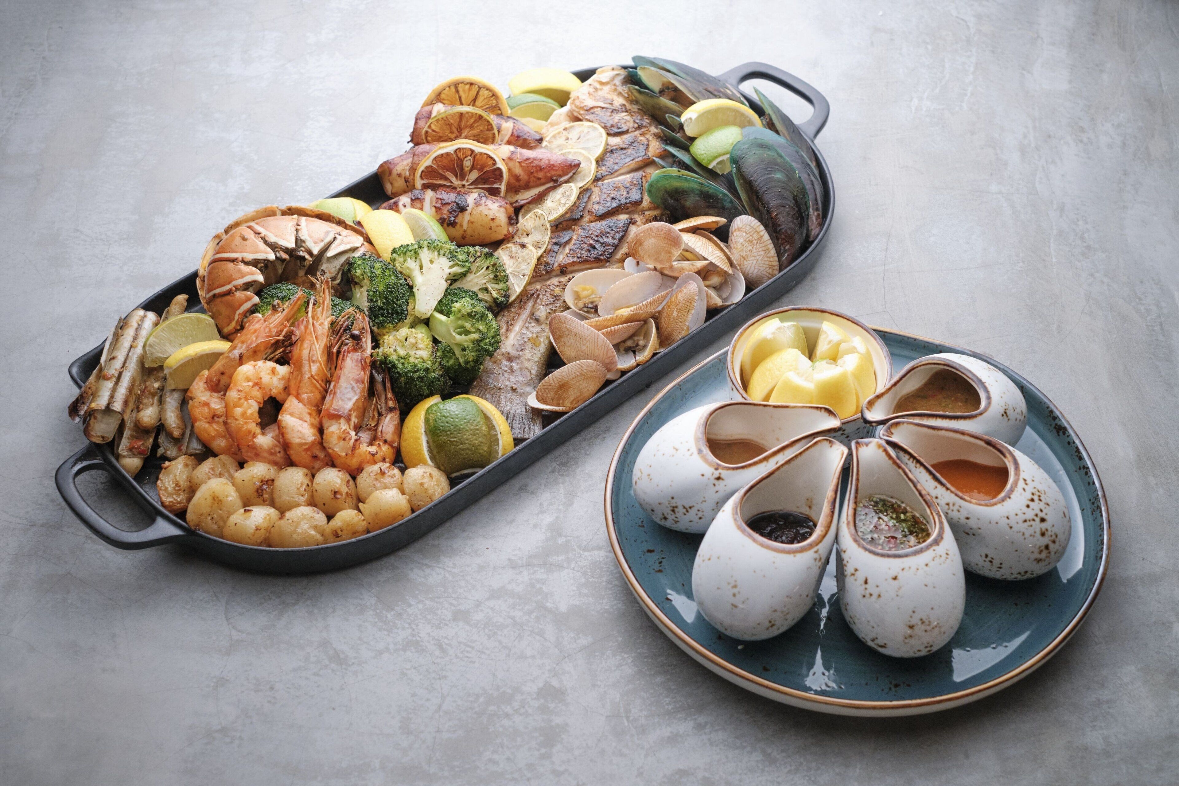 Una bandeja de mariscos con camarones, mejillones, almejas y rodajas de limón.