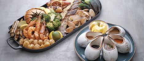 Una bandeja de mariscos con camarones, mejillones, almejas y rodajas de limón.