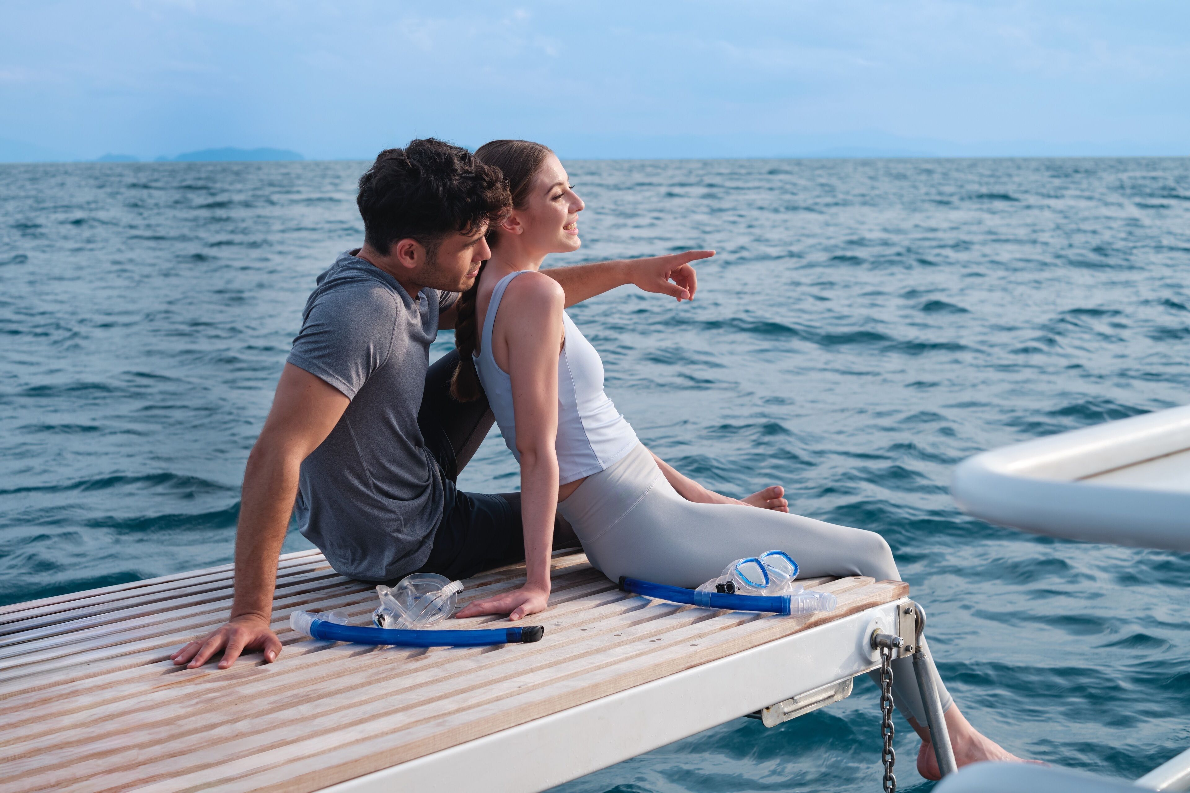 Two people sitting on a wooden deck with a view of the ocean.