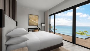 Ein modernes Hotelzimmer mit einem großen Bett, einem Schreibtisch und Blick aufs Meer.