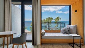 Une chambre moderne avec un balcon, un coin repas et un canapé agrémenté de coussins.