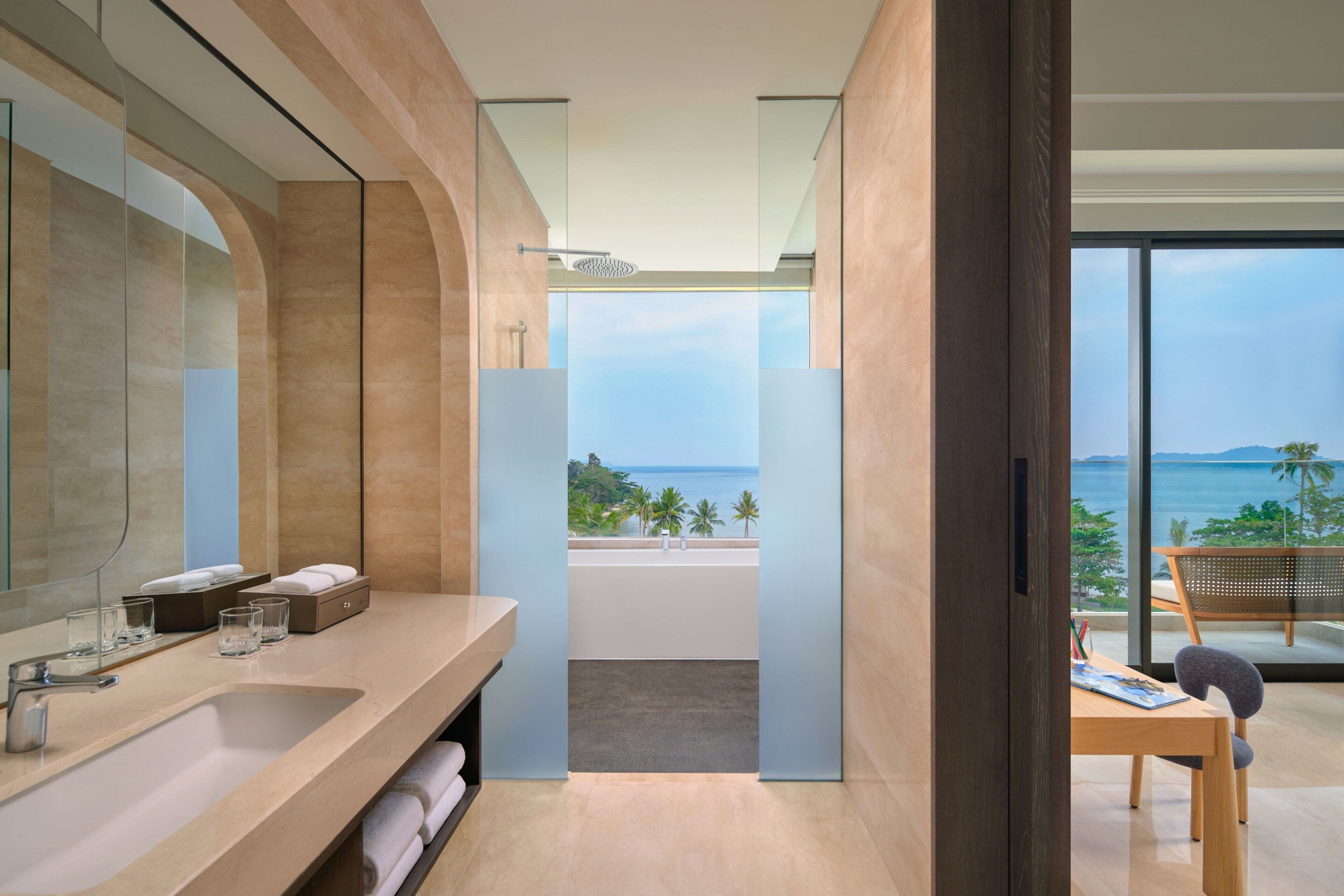 A modern bathroom with a large mirror, a sink, and a view of the ocean.