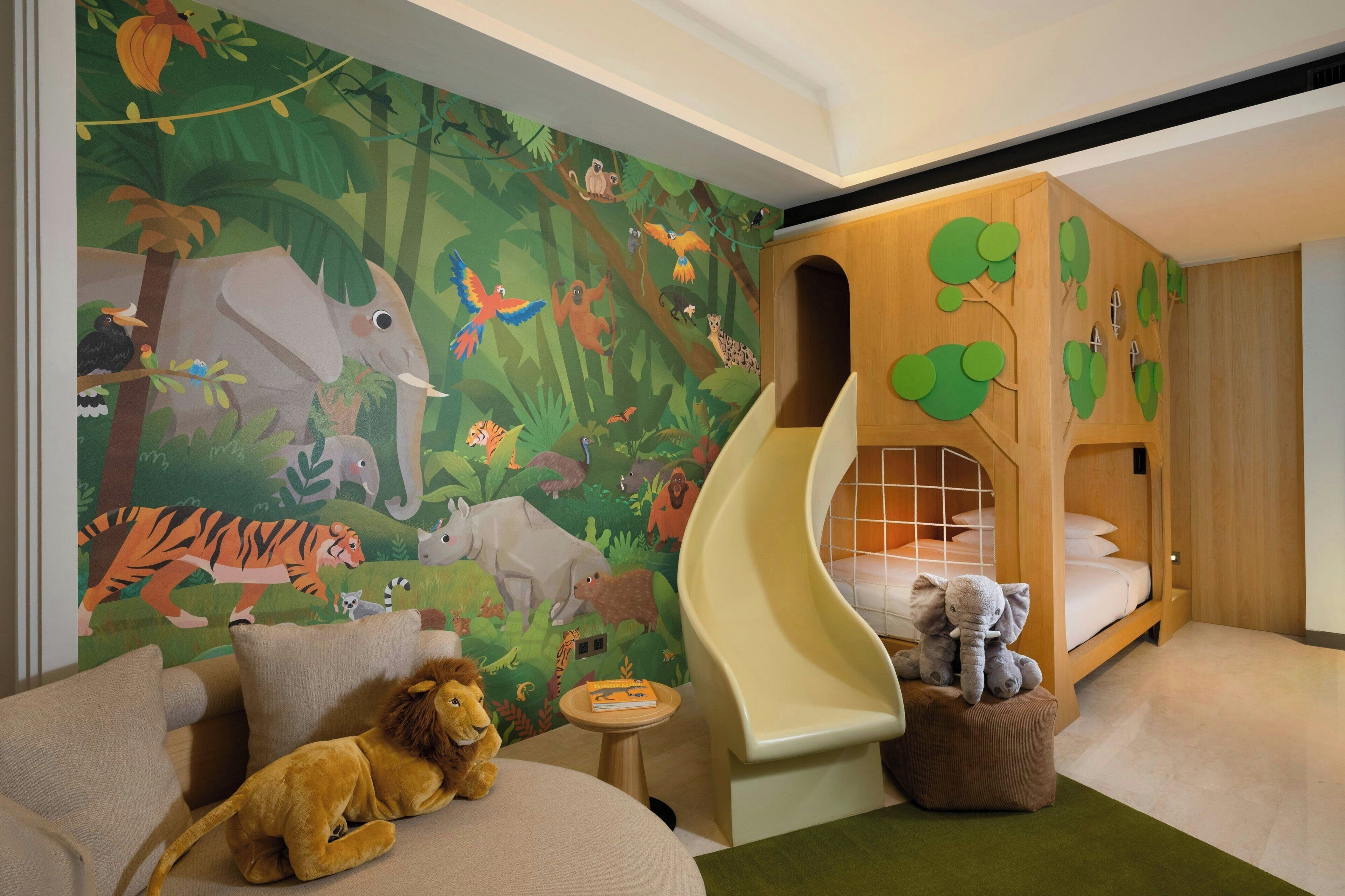A children's room with a jungle-themed mural, a slide, and a cozy seating area.