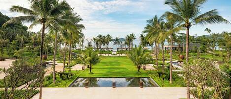 A resort with a central lawn, palm trees, and a swimming pool.