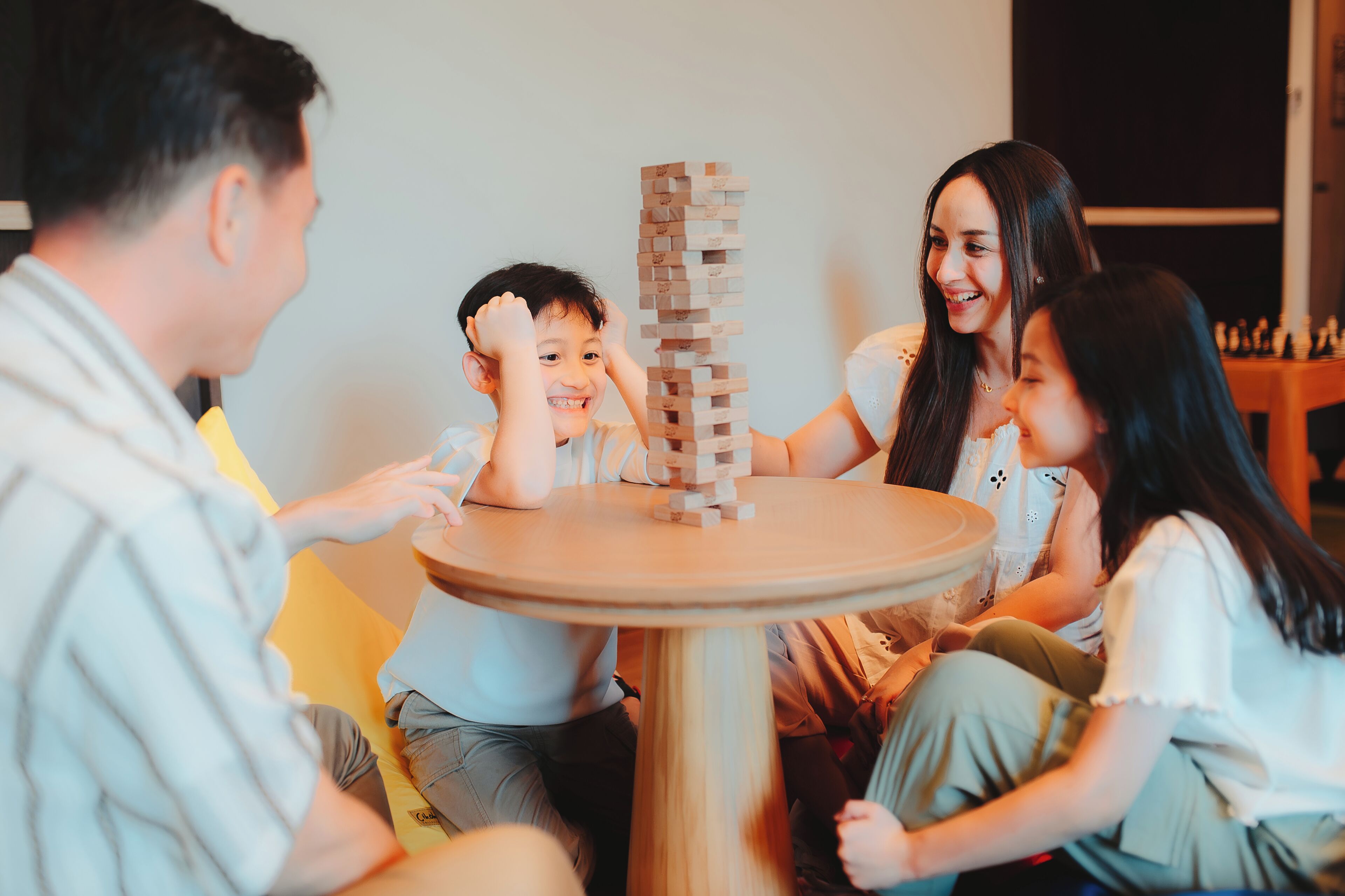 A group of people playing a game of wooden blocks on a round table.