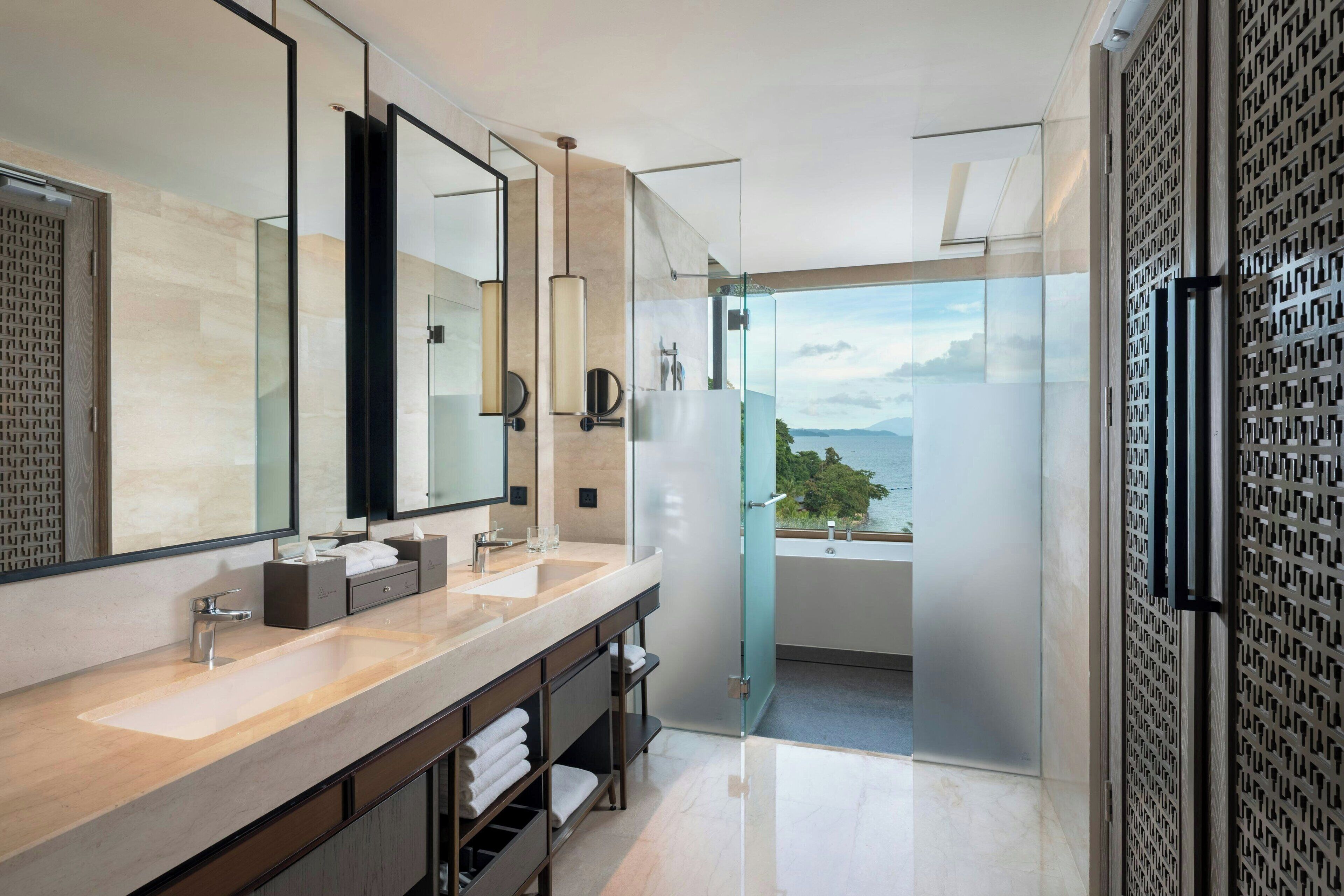 Un baño moderno con un espejo grande, dos lavamanos y una ducha con mampara de vidrio.