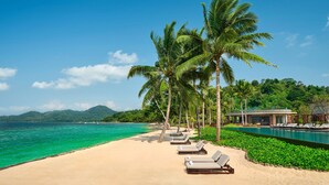 A beach resort with a pool, palm trees, and a view of the ocean. - Lampung Marriott Resort & Spa (Bandar Lampung)