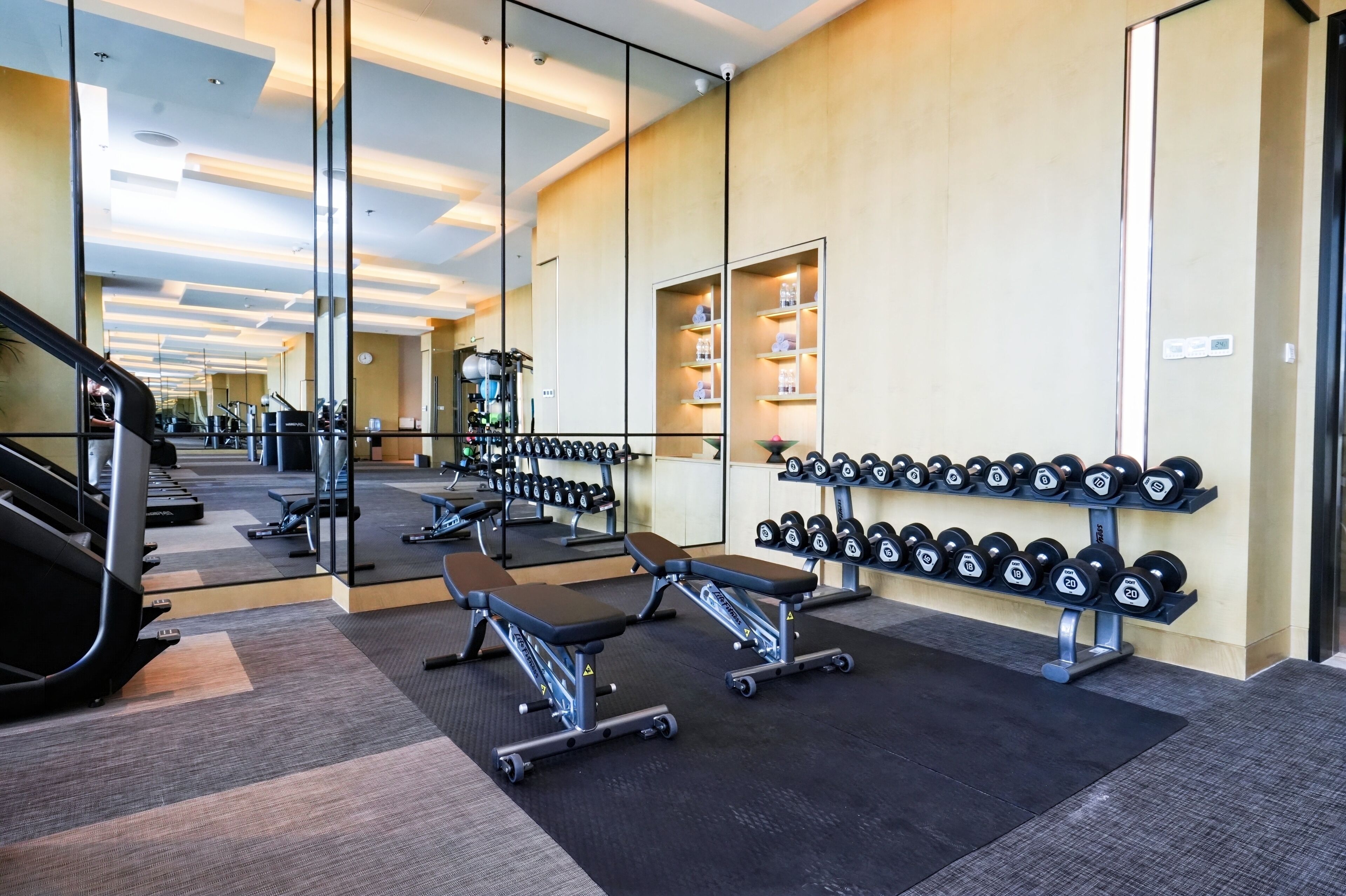Un gimnasio con cintas de correr, mancuernas y bancos.