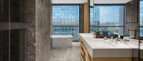 A modern bathroom with a large window, a bathtub, and a vanity with a mirror.