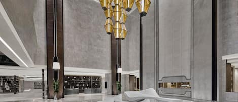 A spacious lobby with a modern chandelier, a reception desk, and a seating area.