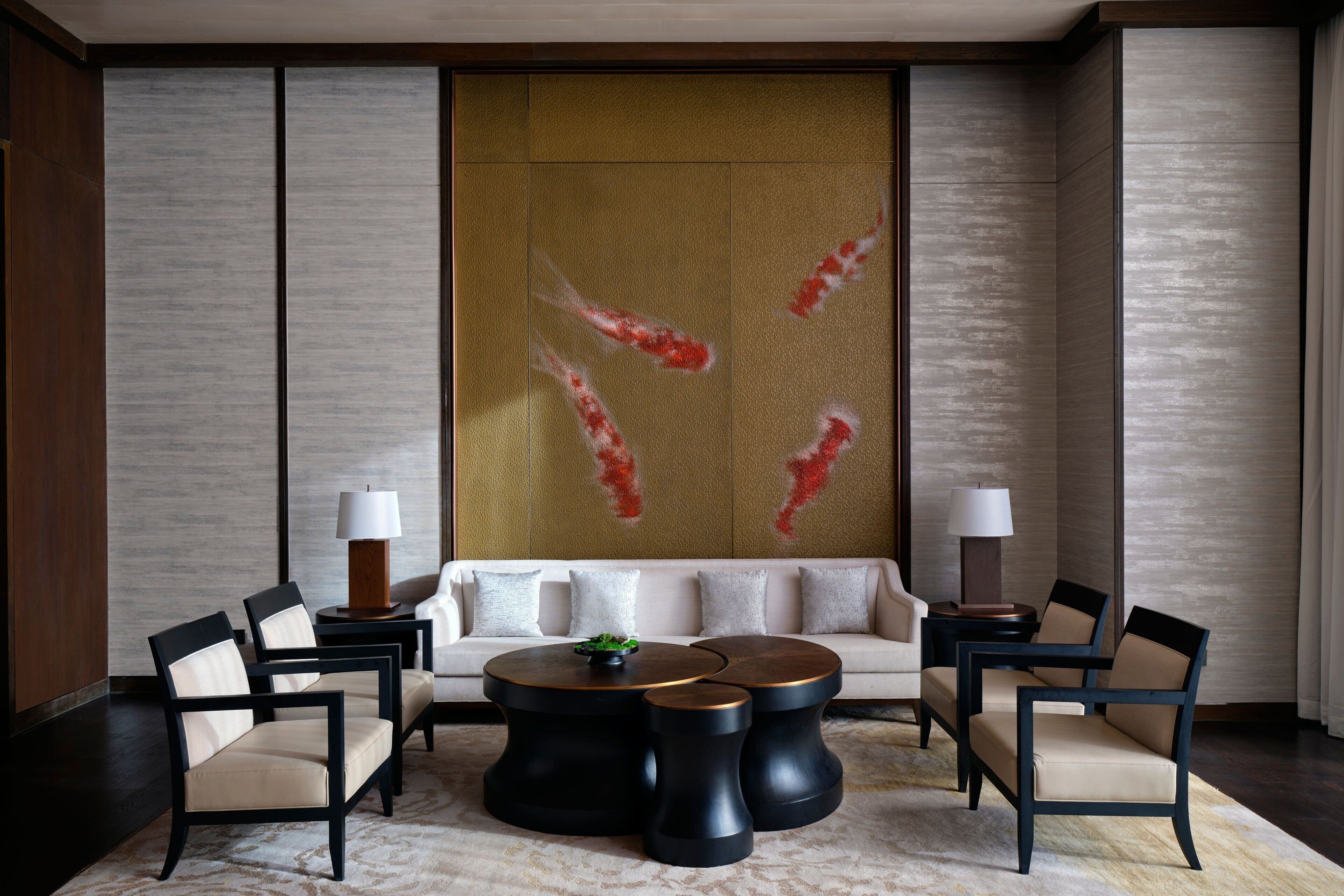 A modern living room with a sofa, two armchairs, a coffee table, and a decorative wall with abstract art.