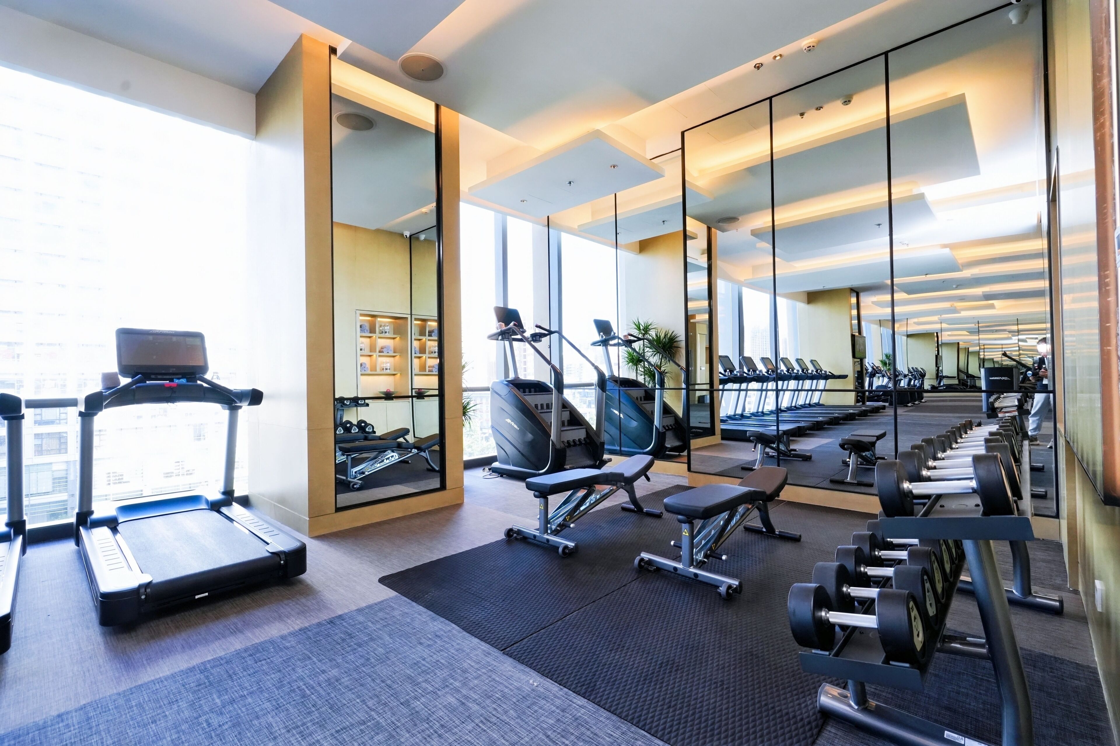 A modern gym with treadmills, stationary bikes, and weight benches.