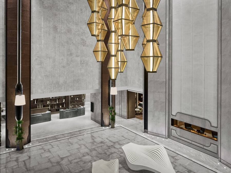A modern lobby with a marble floor, a reception desk, and a fireplace.