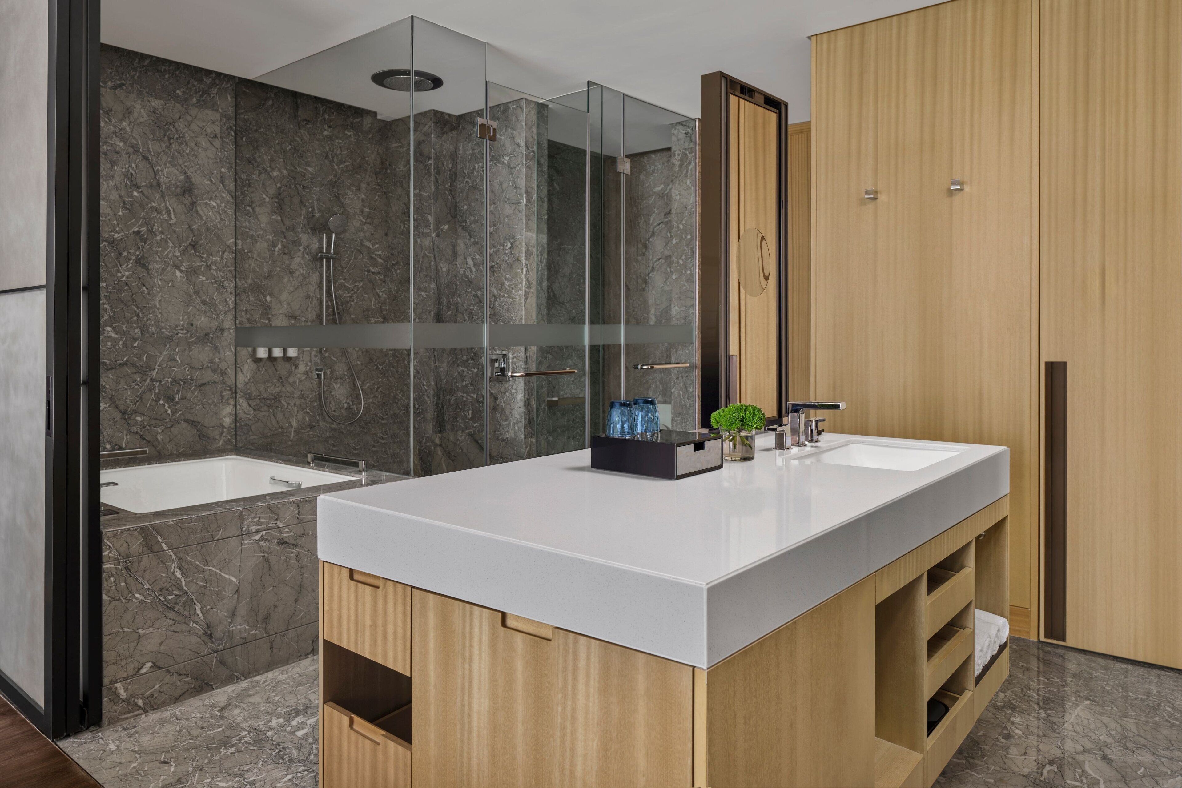 Ein modernes Badezimmer mit großem Spiegel, zwei Waschbecken, einer Dusche und Holzschränken.