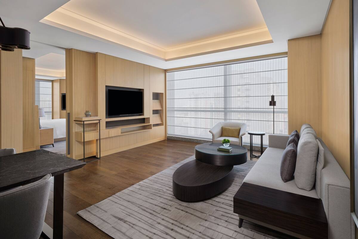 Een moderne woonkamer met een flatscreen televisie, een bank, een salontafel en een eethoek.
