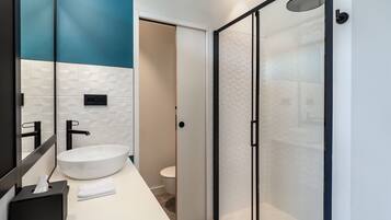 Une salle de bain moderne avec un lavabo blanc, une serviette noire et une douche à parois de verre.