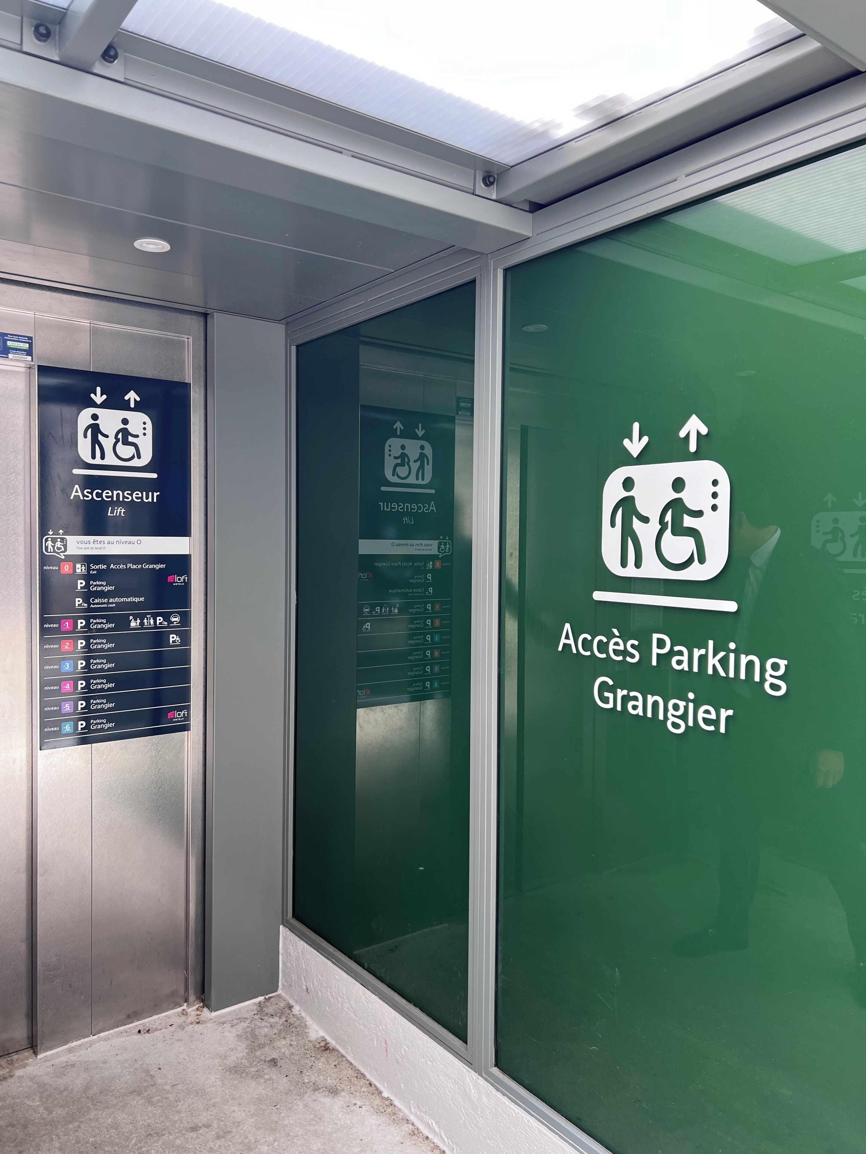 An elevator with a sign indicating access to parking and a ramp.