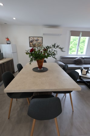 A modern dining area with a rectangular table, black chairs, and a vase with flowers.
