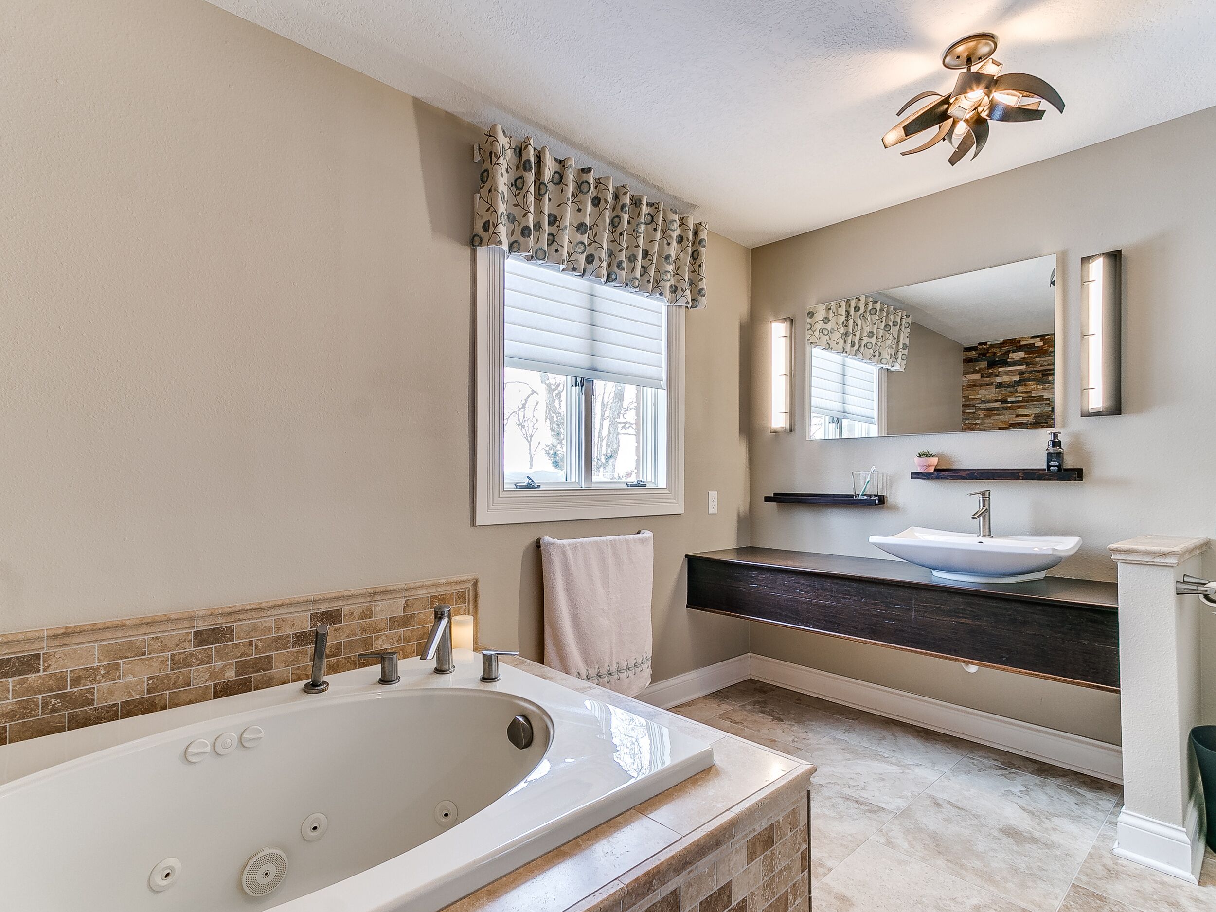 A modern bathroom with a freestanding bathtub, a double sink vanity, and a large mirror.