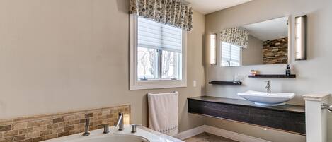 A modern bathroom with a freestanding bathtub, a double sink vanity, and a large mirror.