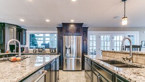 A spacious kitchen with granite countertops, stainless steel appliances, and dark cabinetry. - Huge Retreat with Heated Pool And Hot Tub by Briggs Woods Walking Trail and Golf (Webster City)