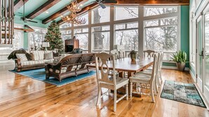 A spacious living room with a wooden ceiling, large windows, a fireplace, and a Christmas tree. - Huge Retreat with Heated Pool And Hot Tub by Briggs Woods Walking Trail and Golf (Webster City)
