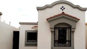 Un bâtiment à la façade blanche, orné d’une arche décorative et doté d ’une fenêtre avec un rideau.