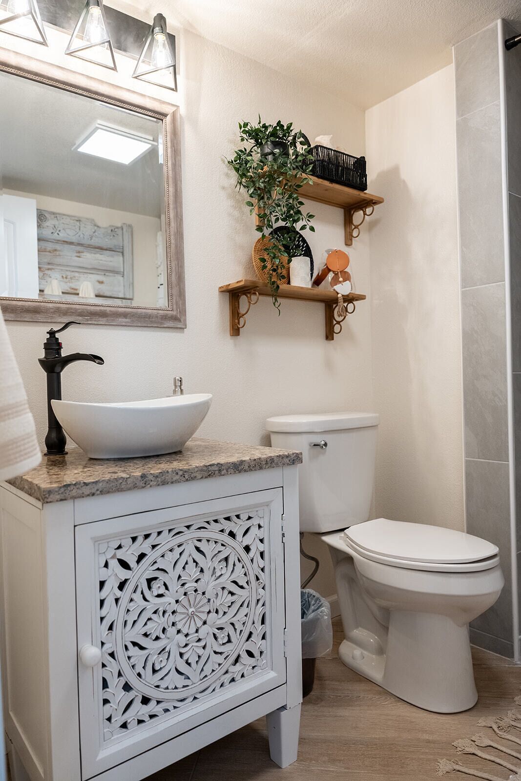 A bathroom with a white vanity, a white sink, a toilet, and a shower area.