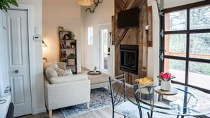 Ein gemütliches Wohnzimmer mit Kamin, Fernseher und Glastisch.