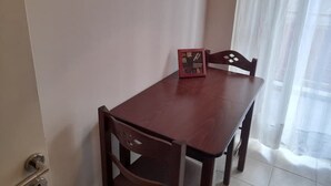 Ein Essbereich mit einem Holztisch und Stühlen, einem gerahmten Bild an der Wand und einem Fenster mit transparenten Vorhängen.