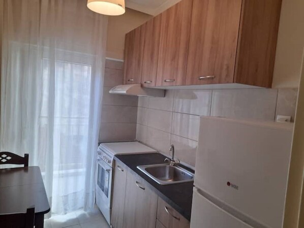 A compact kitchen with wooden cabinets, a stainless steel sink, and a white refrigerator.