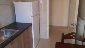 Eine Küche mit Kühlschrank, Spüle und Holzschränken.