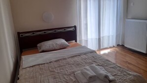 Ein Schlafzimmer mit Bett, Heizkörper und einem Fenster mit Vorhängen.