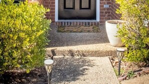 Une maison en briques avec une porte d’entrée sombre, une guirlande et un petit marchepied menant à l’entrée.