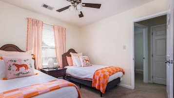 Ein Schlafzimmer mit zwei Betten, einem Deckenventilator, einem Fenster mit Vorhängen und einer Tür.