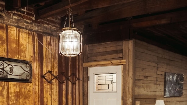 A rustic wooden interior with a dining table and chairs, a hanging light fixture, and a door with a window. - The Loft on Main (Belmont)
