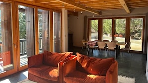 Un vaste espace de vie doté d’un plafond en bois, de grandes fenêtres et d’un canapé rouge.