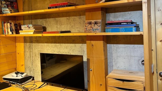 Un interior de madera con un escritorio, estanterías llenas de libros y un televisor.