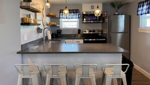 A modern kitchen with a central island, stainless steel appliances, and pendant lighting.
