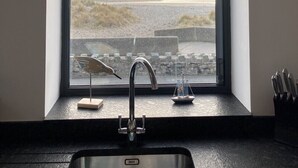 A kitchen with a window overlooking a beach, a modern faucet, and a knife block. - Beach Haven (Hafan y Traeth)  (Barmouth)