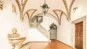 A grand hallway with a marble bust, a staircase with ornate railings, and a wooden door. - Lusso e Charme
Wonderful apartment in the city center of Florence! (Firenze)